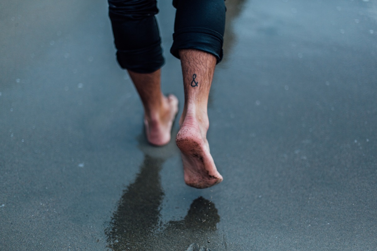 man walking bearfoot on asphalt road