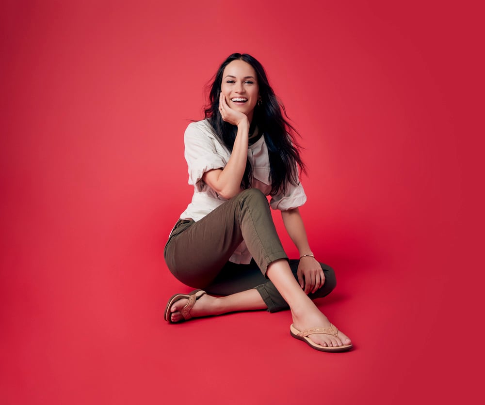Smiling woman sitting on the floor in sandals