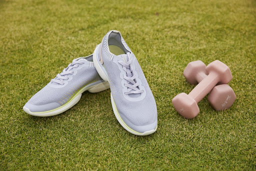 Pair of sneakers and dumbells on the grass
