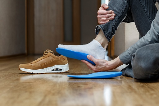 Man putting new custom insole in a shoe. Feet recreation medicine concept