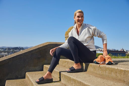 Woman sitting down on a stairwalk after jogging
